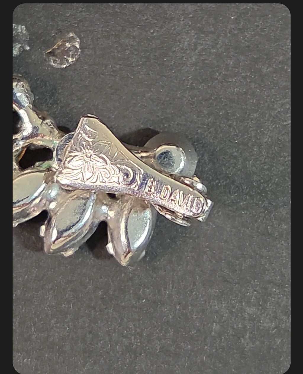 Oddly Darling Vintage B. David clip-on earring back showing floral engraving and signature hallmark on silver-tone metal