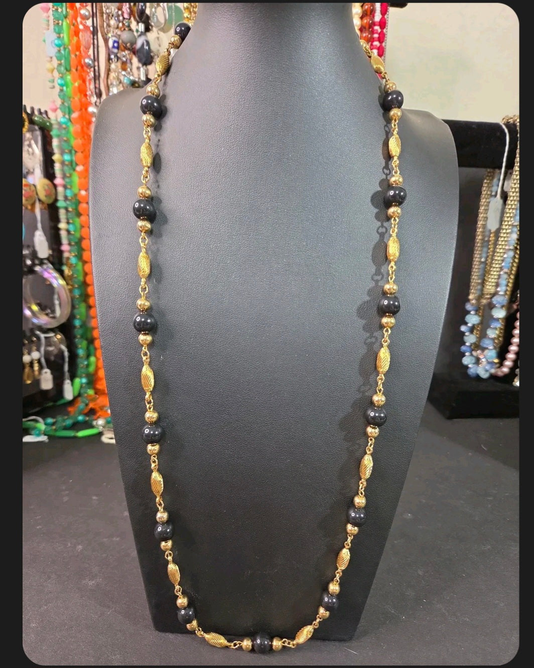 Oddly Darling Vintage long necklace with polished black beads and textured gold-tone metal spacers on a display bust.