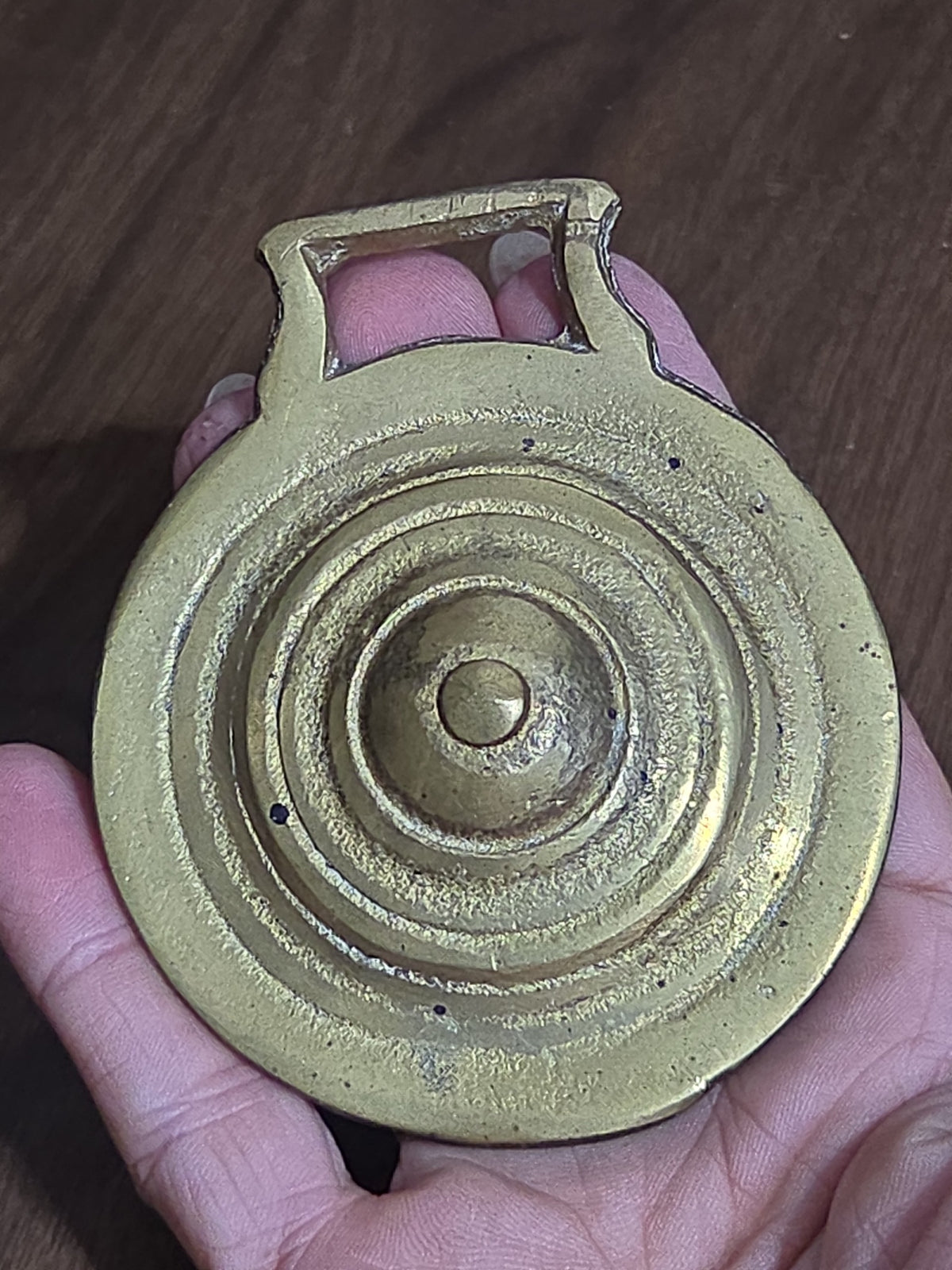 Oddly Darling Vintage brass horse harness medallion with concentric ring design and warm patina held in a hand