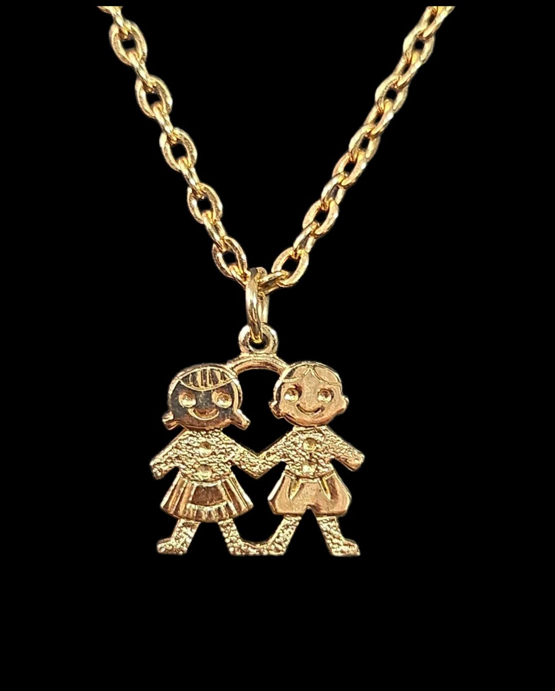 Oddly Darling Vintage gold-tone necklace featuring a pendant of two children holding hands with textured detailing.