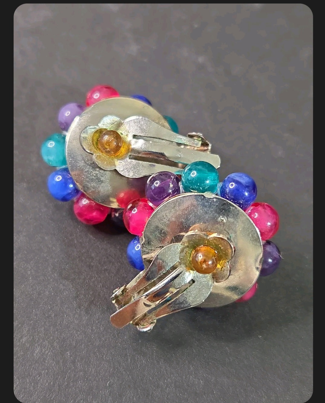Oddly Darling Vintage multi-colored cluster bead clip-on earrings with silver-tone backings on a dark background.