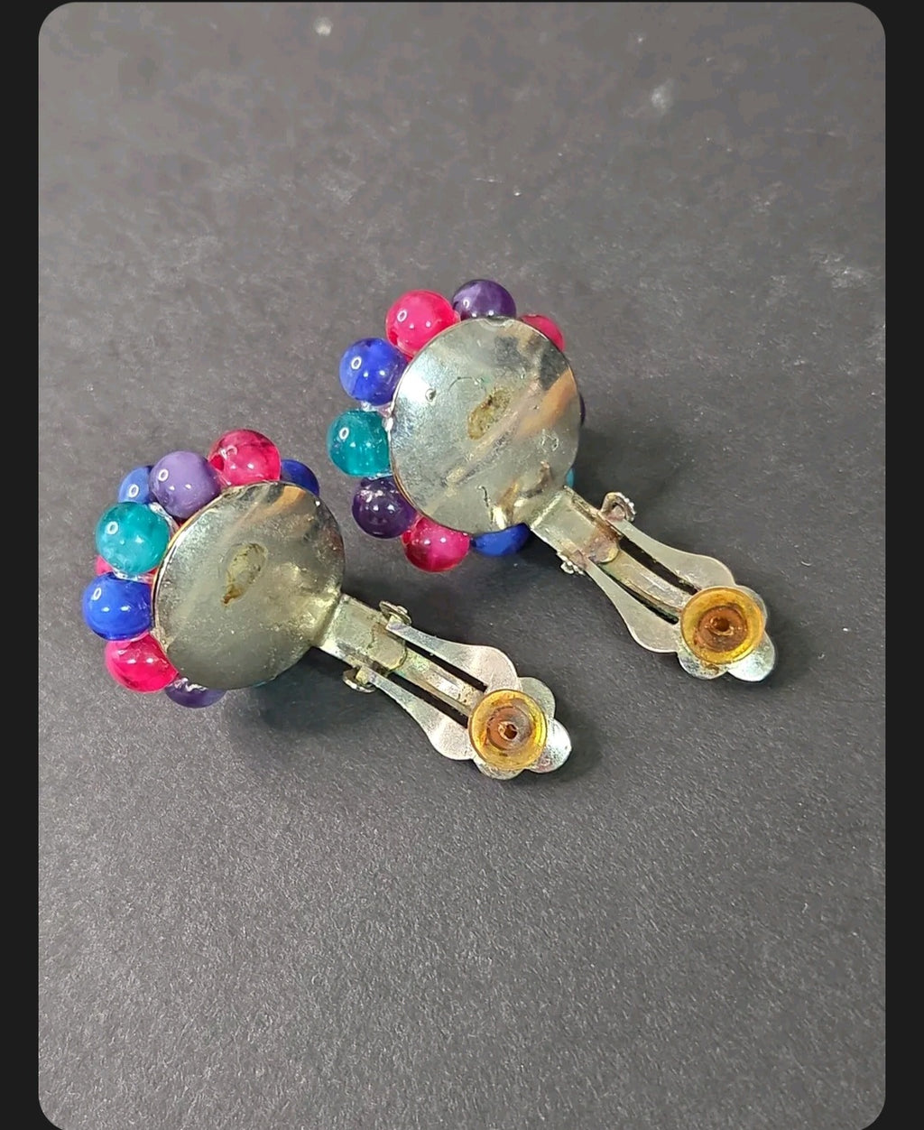 Oddly Darling Vintage multi-colored cluster bead clip-on earrings with silver-tone backings on a dark background.