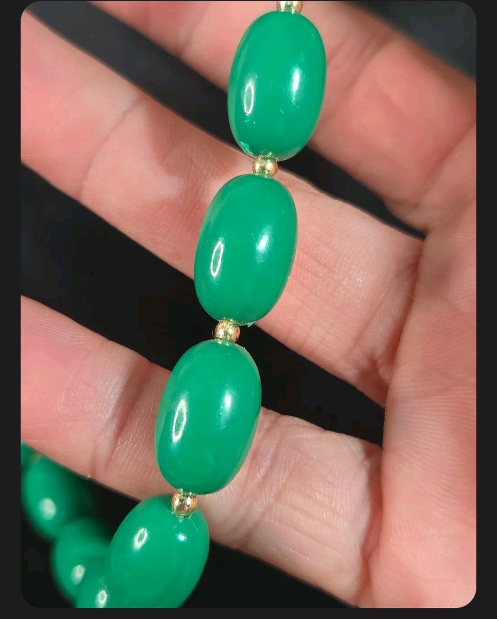 Oddly Darling Vintage emerald green oval bead necklace with gold-tone spacers held in a hand