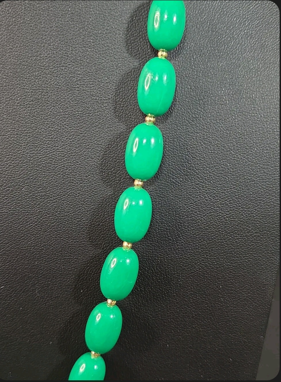 Oddly Darling Vintage emerald green oval bead necklace with gold-tone spacers on a black display stand