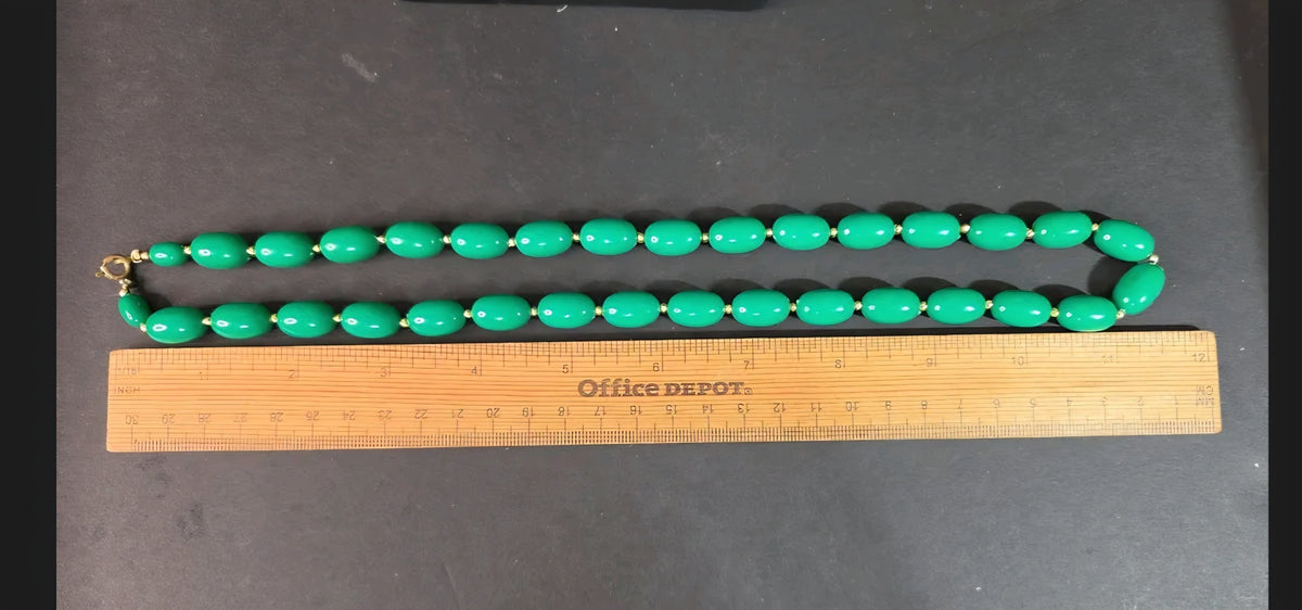 Oddly Darling Vintage emerald green oval bead necklace with gold-tone accents laid flat against a wooden ruler