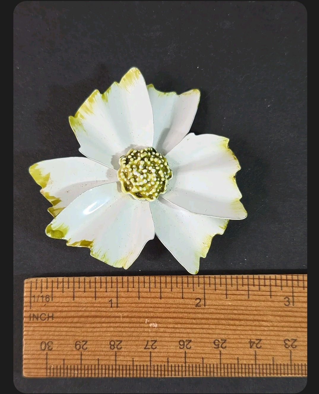 Oddly Darling Vintage enamel flower brooch with white petals, green tips, and a textured beaded center on black.