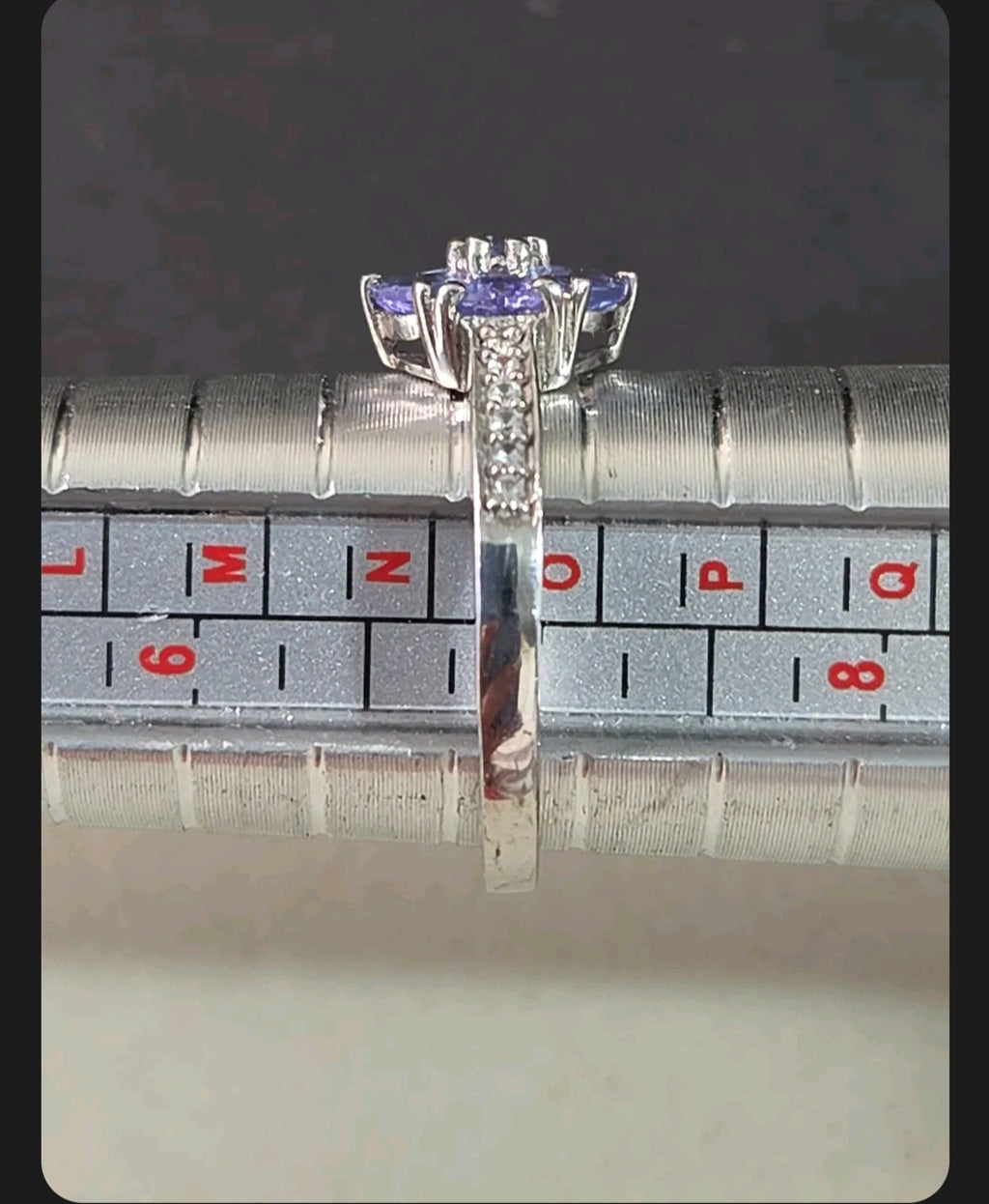Oddly Darling Vintage floral cluster ring with violet gemstones and accent stones on a metal ring sizing mandrel