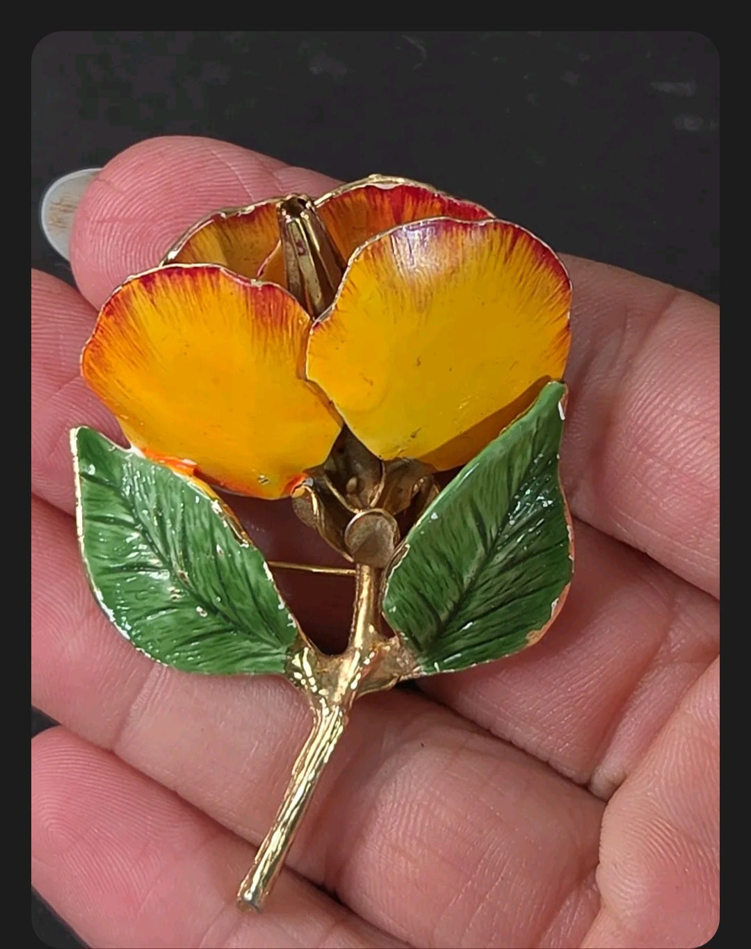 Oddly Darling Vintage floral brooch with yellow and orange enamel petals and green leaves on a gold-tone stem.