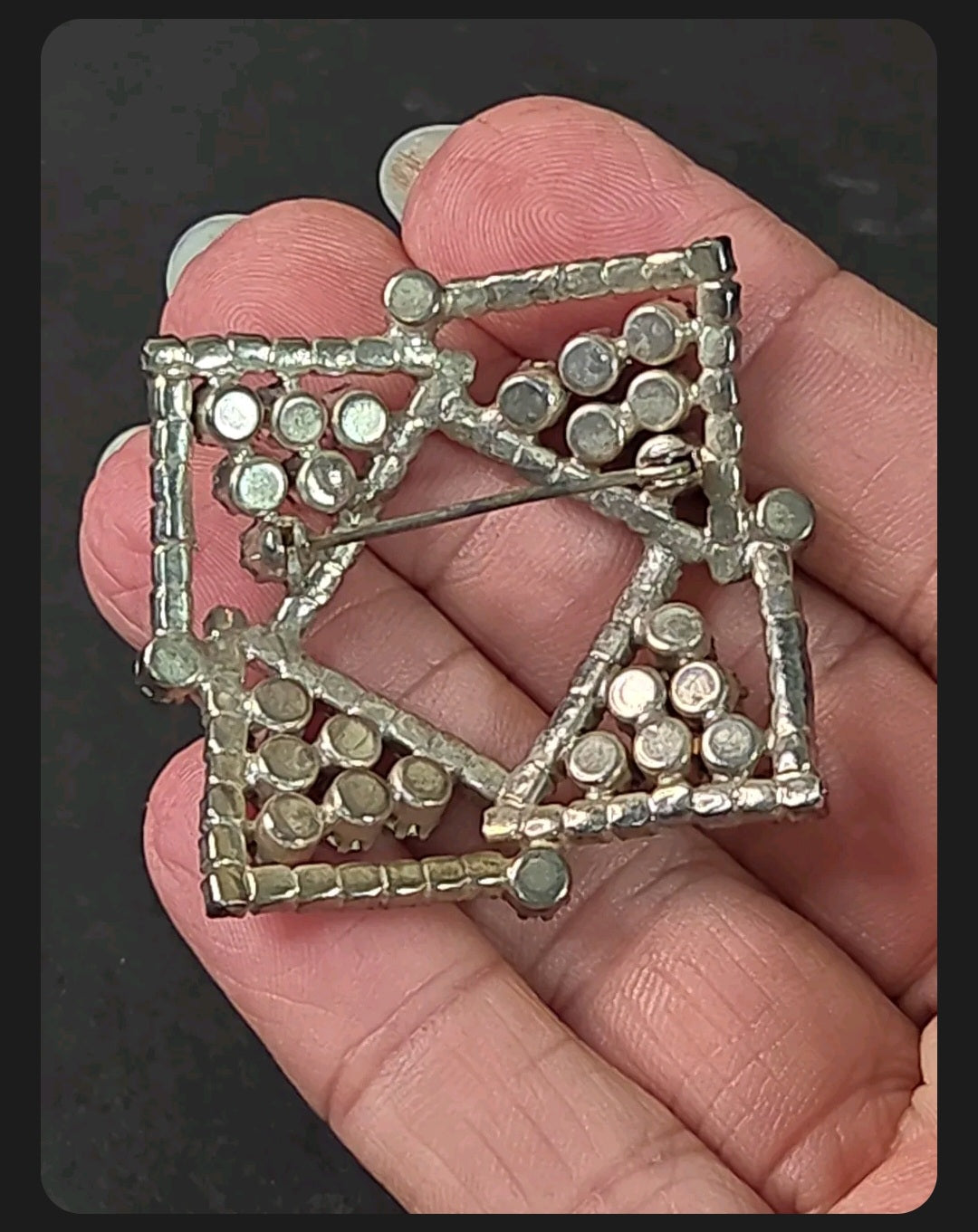 Oddly Darling Vintage geometric brooch with clear crystals and blue stones held in a palm for scale.