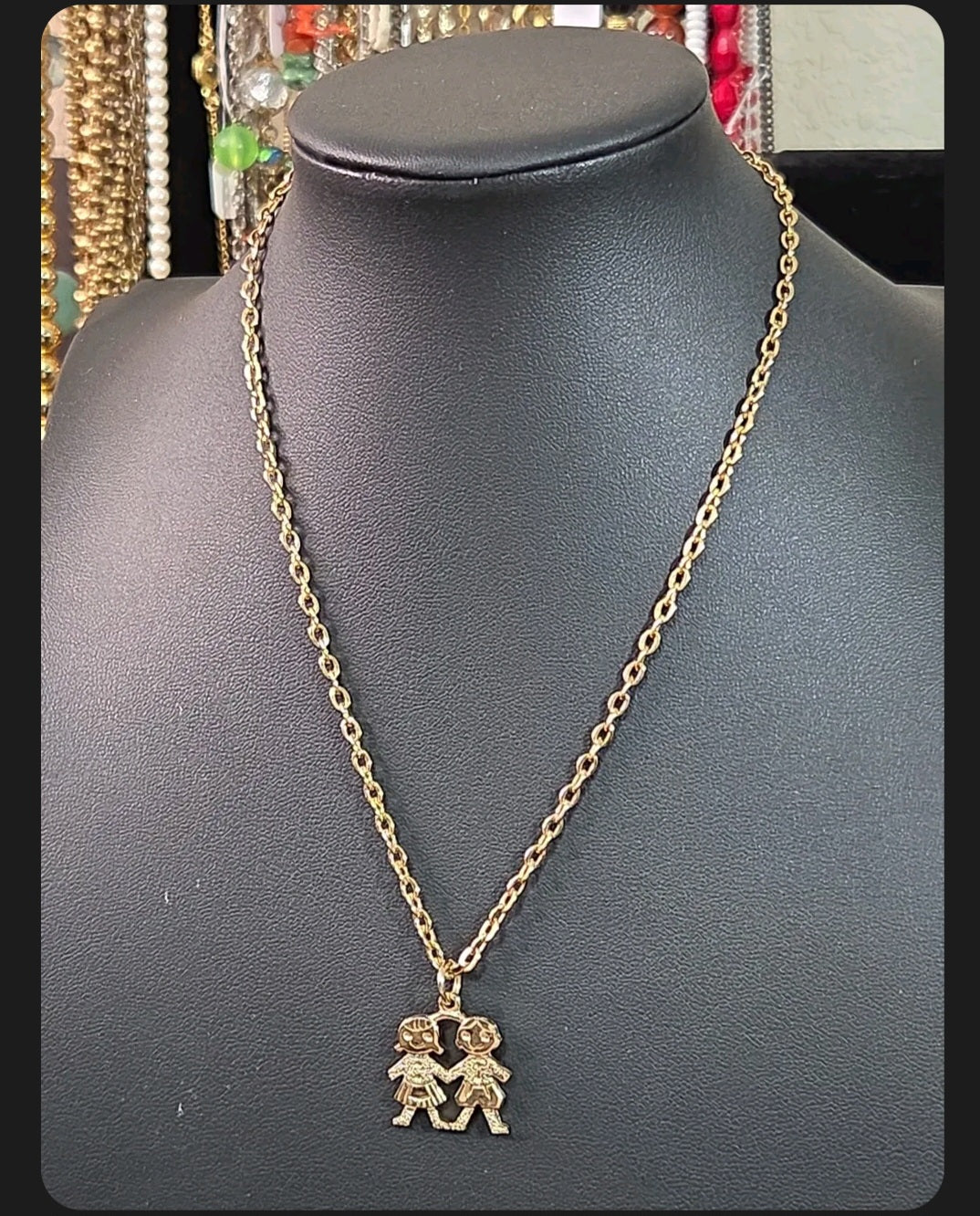 Oddly Darling Vintage gold-tone necklace featuring a pendant of two children holding hands on a delicate chain.