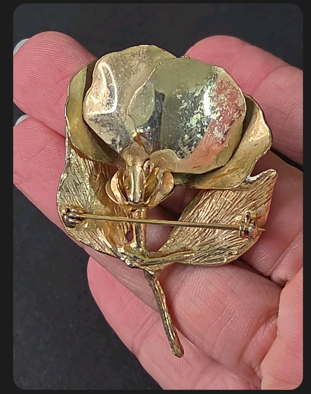 Oddly Darling Vintage gold-tone floral brooch pin with textured metal leaves held in a hand, back view.