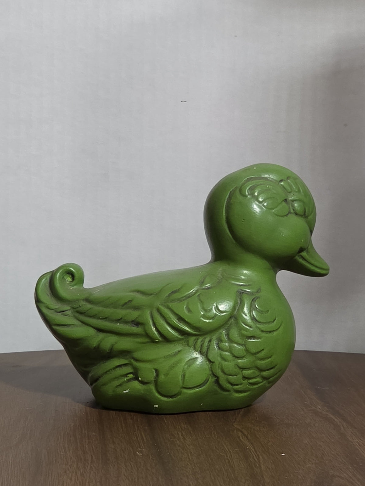 Oddly Darling Vintage ceramic duck figurine in matte green with embossed feather details on a wooden surface.