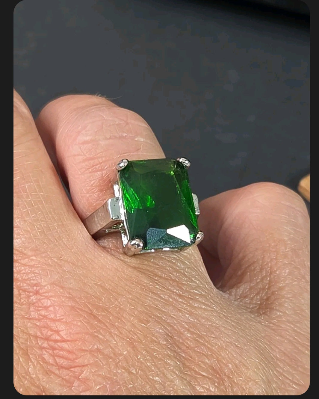 Oddly Darling Vintage emerald-cut green statement cocktail ring in a silver-tone four-prong setting on a finger