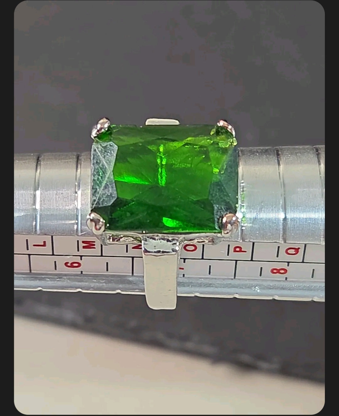 Oddly Darling Vintage emerald-cut green gemstone cocktail ring in a silver-tone four-prong setting on a ring sizer