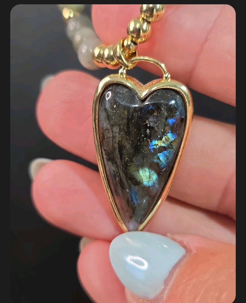 Oddly Darling Vintage heart-shaped Labradorite pendant necklace with gold-tone beads held in a hand.