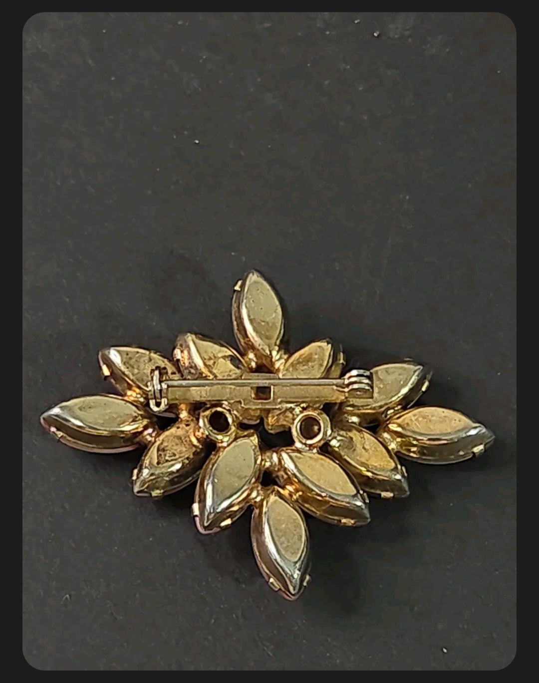 Back view of an Oddly Darling Vintage marquise stone cluster brooch with a gold-tone pin closure on a dark background.