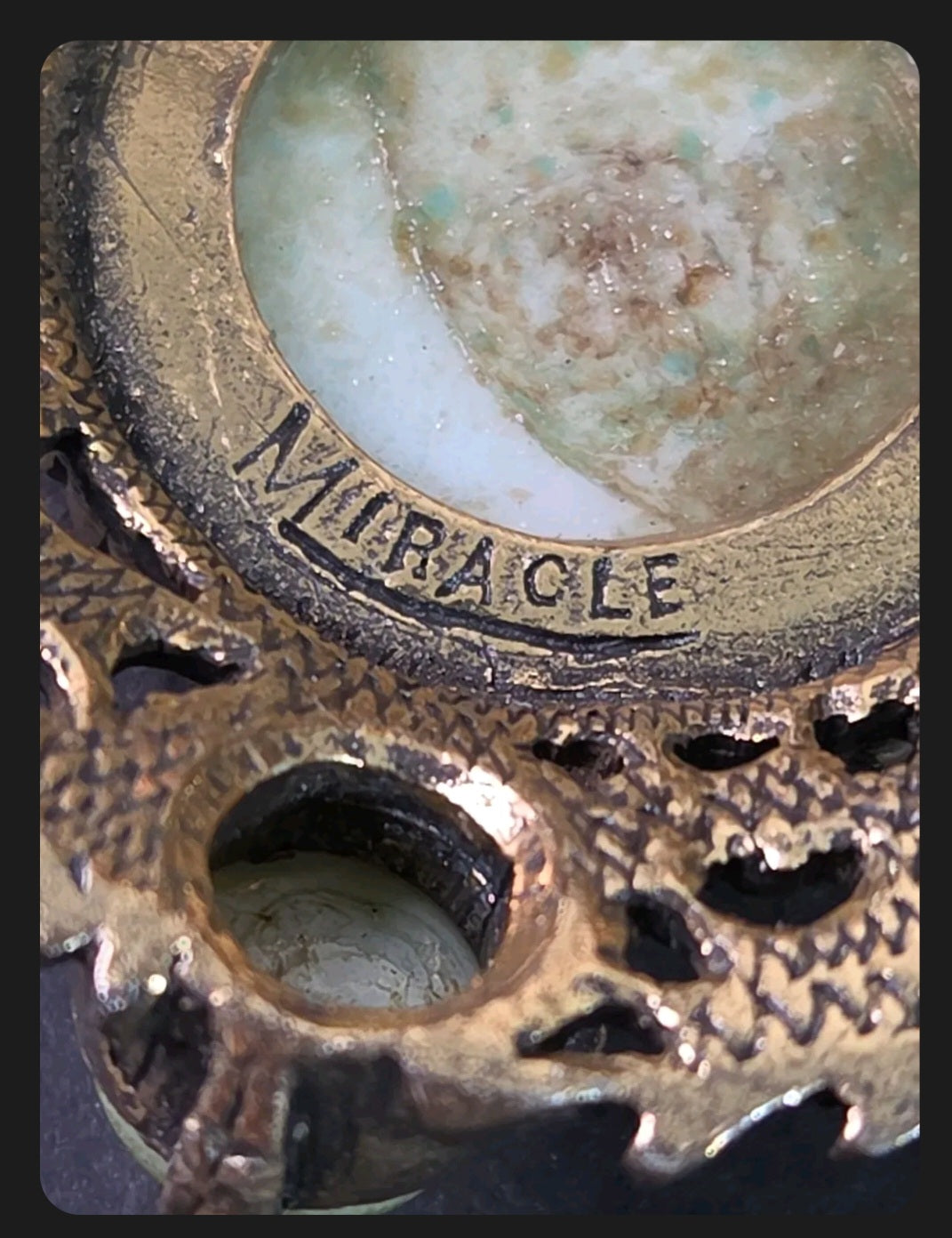 Oddly Darling Vintage Miracle brooch detail showing the signature hallmark on antique gold metal and green cabochon