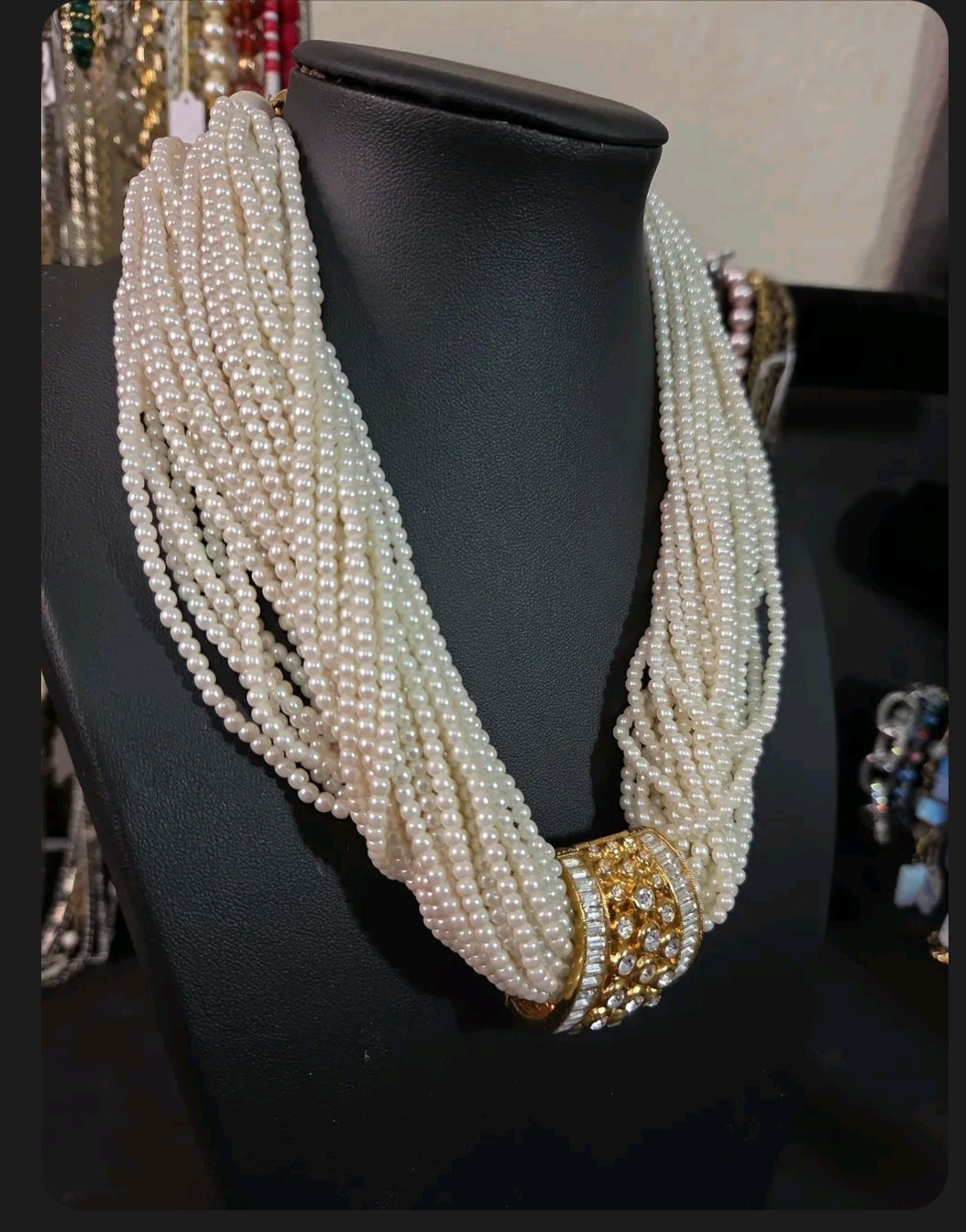 Oddly Darling Vintage multi-strand cream faux pearl necklace with a gold-tone rhinestone centerpiece on a display bust