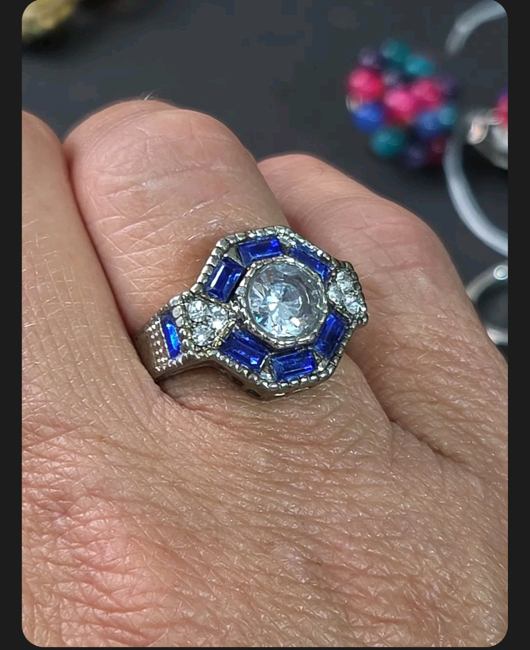 Oddly Darling Vintage ornate statement ring with a round central stone, blue baguette accents, and textured band.