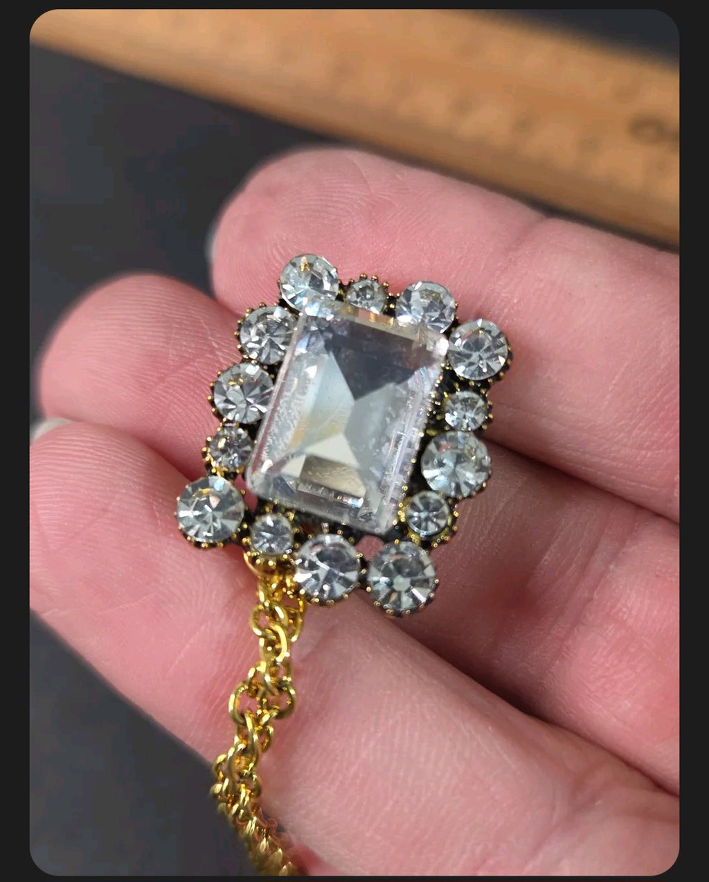 Oddly Darling Vintage ornate gold-tone brooch featuring a large rectangular clear crystal surrounded by smaller stones.