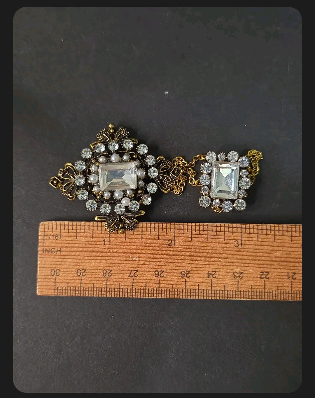 Oddly Darling Vintage ornate double brooch with gold-tone chains, clear crystals, and faux pearls on a ruler.