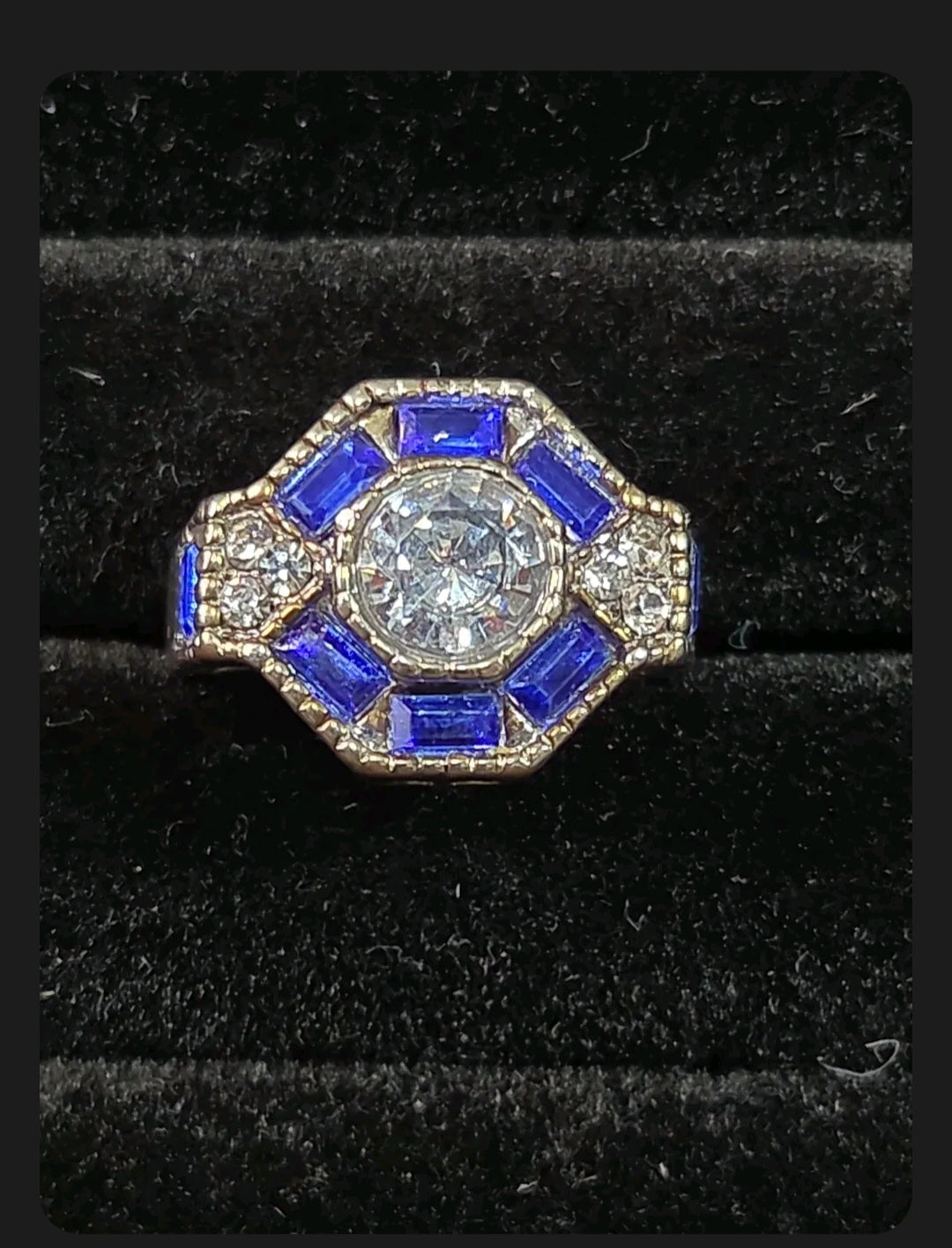 Oddly Darling Vintage ornate statement ring with a round central stone, blue baguette accents, and textured band.