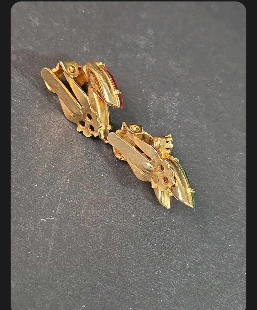 Oddly Darling Vintage gold-tone clip-on earrings with ruby red and emerald green marquise crystals on a dark surface