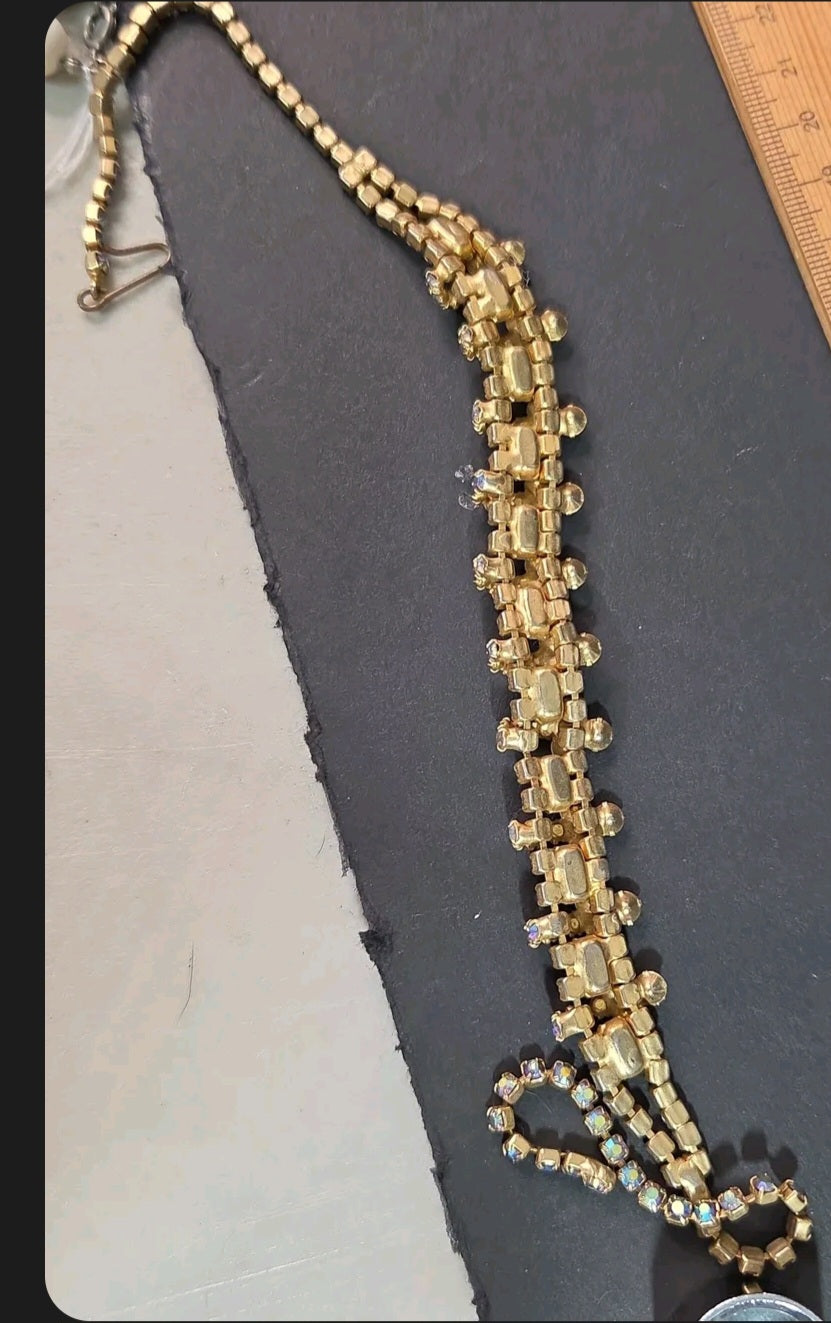 Oddly Darling Vintage gold-tone statement necklace with orange and iridescent rhinestones on a dark display surface.