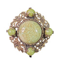 Oddly Darling Vintage brooch featuring a sage-green mottled cabochon in an antique-gold leaf and acorn metal frame.