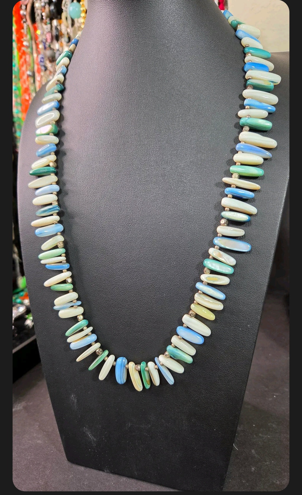 Oddly Darling Vintage statement necklace featuring elongated multi-colored shell beads in ocean blue, green, and white.