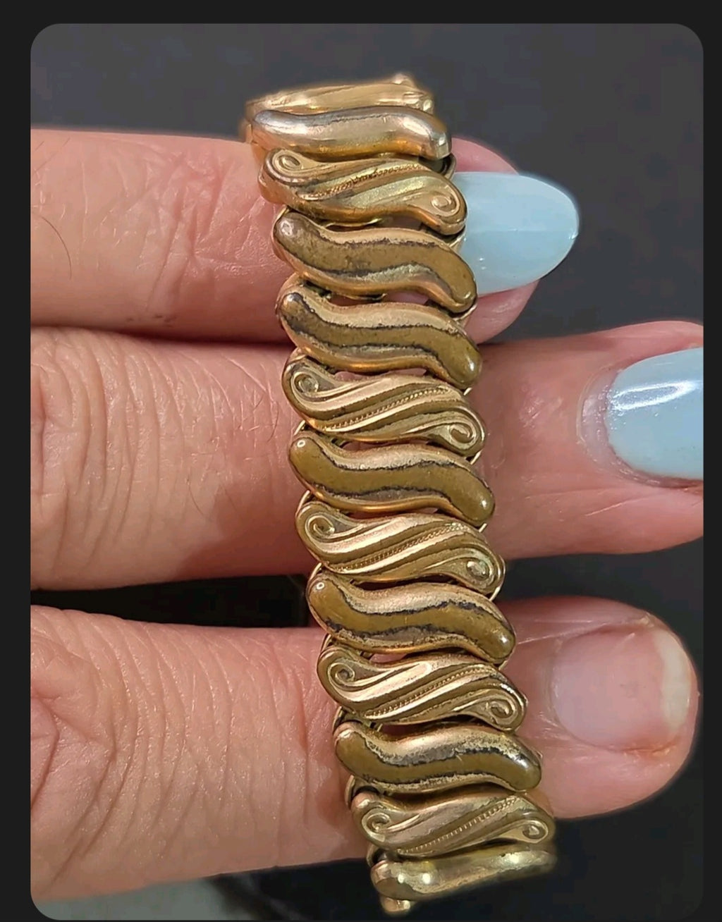 Oddly Darling Vintage Speidel gold-tone expansion bracelet with intricate wave-patterned links on a wrist.