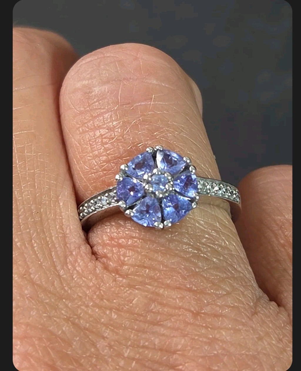 Oddly Darling Vintage floral cluster ring featuring violet gemstones and accent stones on a silver band on a finger